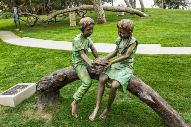 Bronze Sculpture of Two Children Sitting on a Log